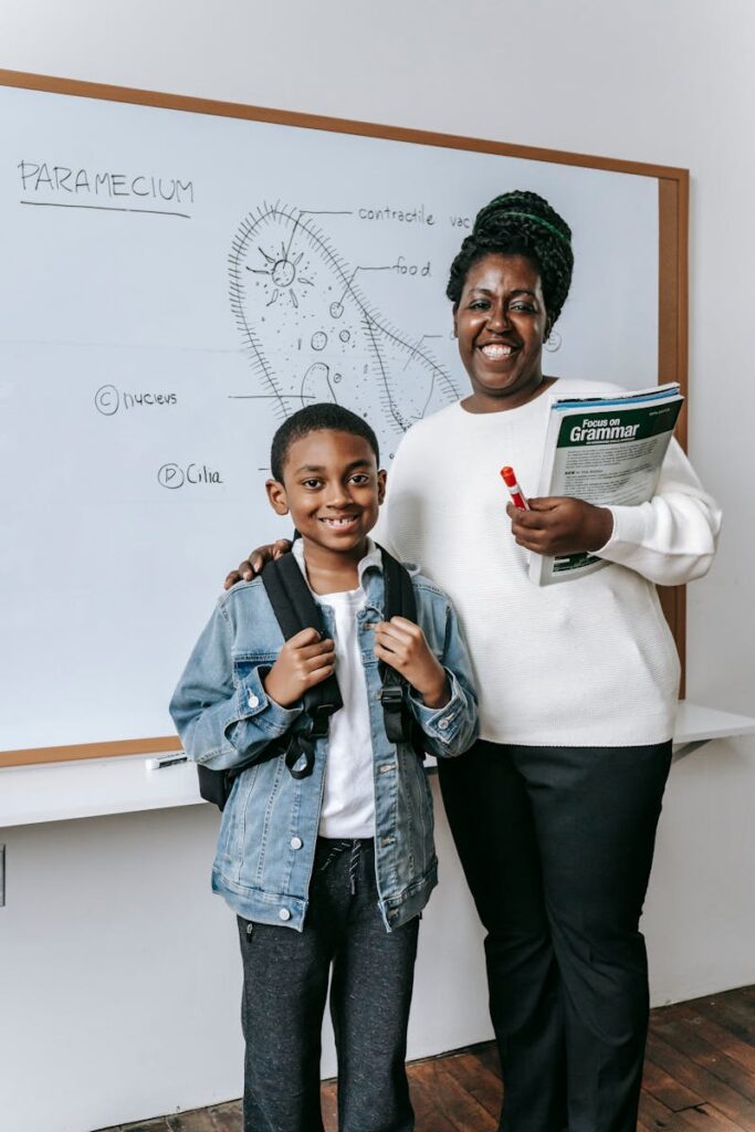 A cheerful teacher and student pose in front of a biology whiteboard.